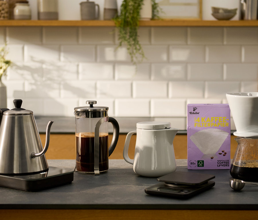 Auf einer Küchentheke stehen ein Kaffeebereiter aus Keramik, ein elektrischer Schwanenhalskessel, eine Kaffeewaage mit Timer, ein Kaffee Handfilter und eine Siebstempelkanne.