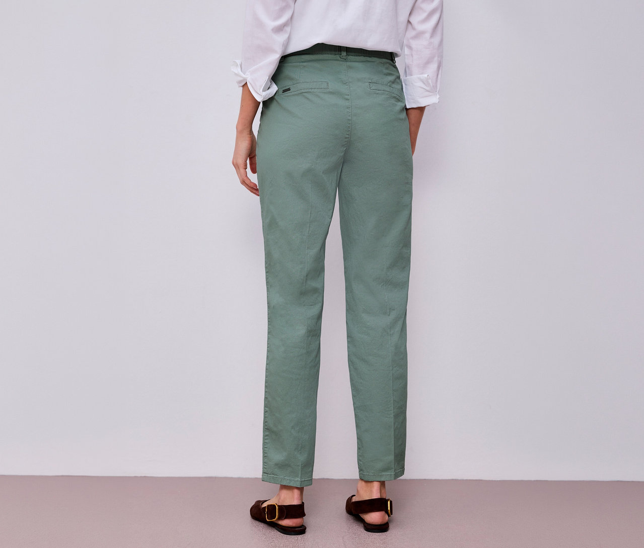 Rückansicht einer Frau mit weißem Hemd und Street One Chino in Mint, dazu braune Sandalen.