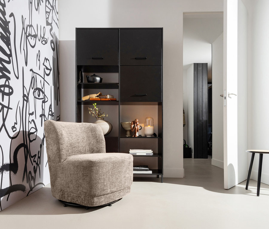 WOOOD Drehsessel »Atty« in Sand steht vor einem schwarzen Regal und einer Wand mit grafischem Muster.