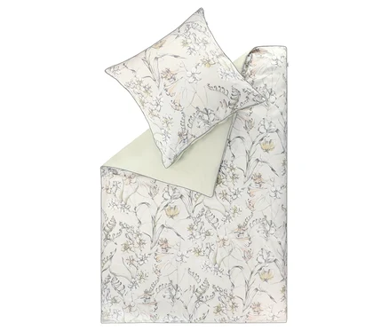 SCHÖNER WOHNEN-Kollektion Bettwäsche »LOVELY« mit floralem Muster. Die Bettdecke ist gefaltet und zeigt eine hellgrüne Rückseite. Das Muster zeigt helle Blüten und grüne Blätter auf hellem Grund. Ein passender Kissenbezug liegt obenauf.