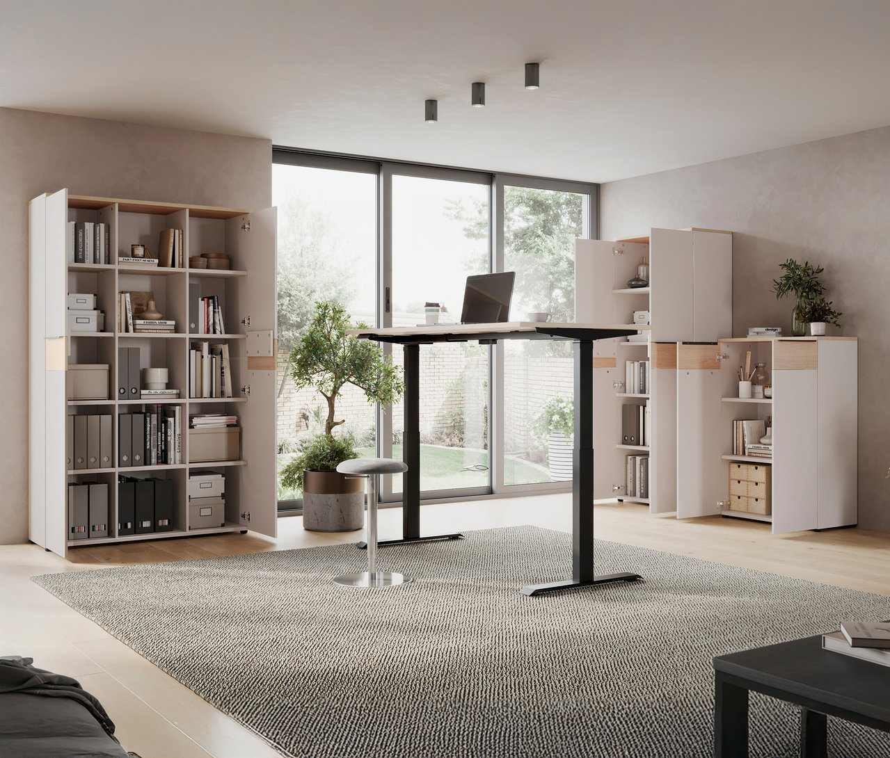 Ein »Oviedo« höhenverstellbarer Schreibtisch steht in einem Raum mit Regalen und einem Fenster.