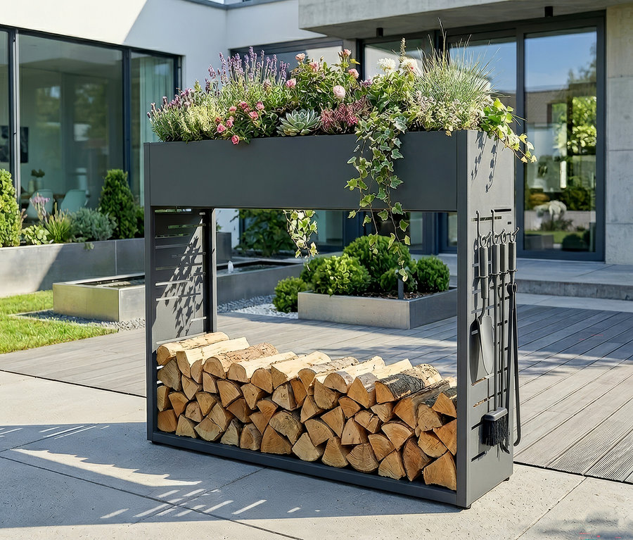 Dunkelgraues Metallregal mit oben bepflanztem Blumenkasten, gefüllt mit Lavendel, rosa Rosen, Sukkulenten und Efeu. Darunter ist Brennholz gestapelt, und seitlich hängt Kaminbesteck.