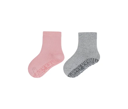 Zwei Socken, eine rosa und eine graue, beide mit Anti-Rutsch-Sohlen.