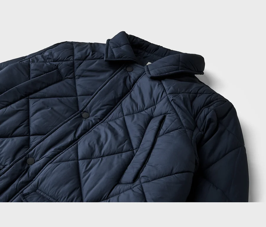 Nahaufnahme einer dunkelblauen Steppjacke mit Rautenmuster, schwarzen Knöpfen und Kragen.