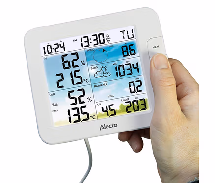 Weiße digitale Wetterstation mit farbigem Display, das Zeit, Innen- und Außentemperatur, Luftfeuchtigkeit, Wind, Luftdruck, Regen, UV und Licht anzeigt. Eine Hand drückt die MEM-Taste.