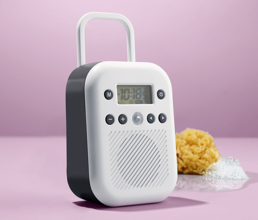Ein weißes Badradio steht neben einem gelben Badeschwamm und einem Haufen weißen Schaums.