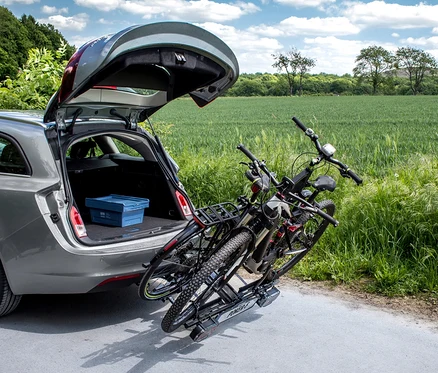 Zwei Fahrräder auf einem »Poker-F« Fahrradträger an einem grauen Auto mit geöffnetem Kofferraum.