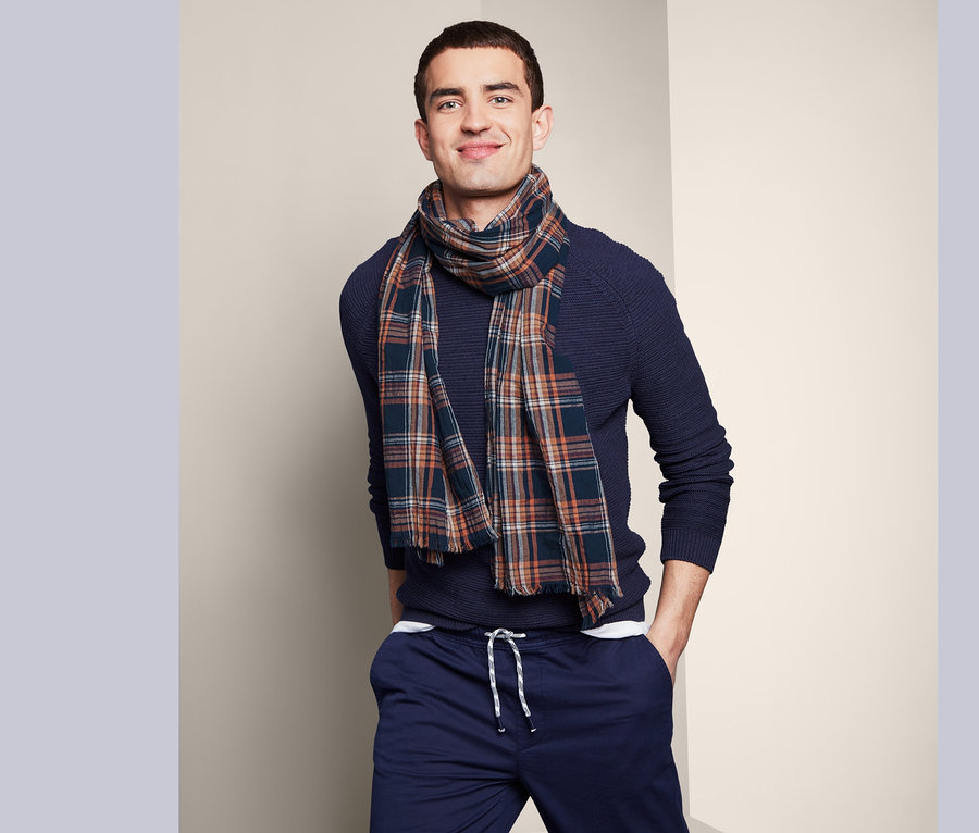 Mann trägt einen Webschal und einen dunkelblauen Pullover.