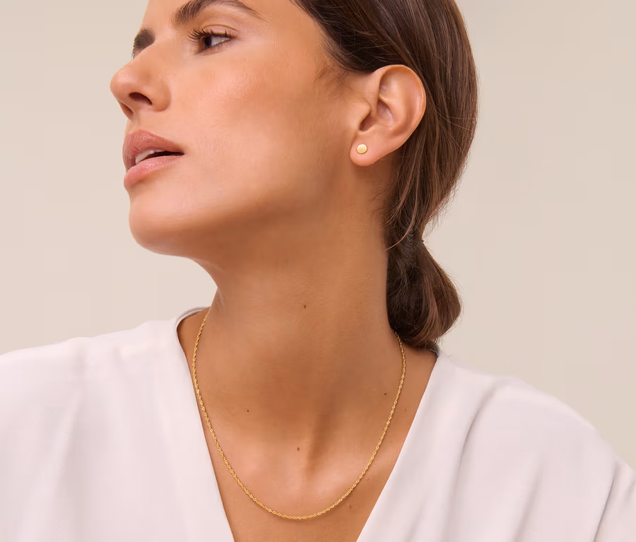 Frau trägt eine goldene Singapur Kette und goldene Classic Ohrstecker.