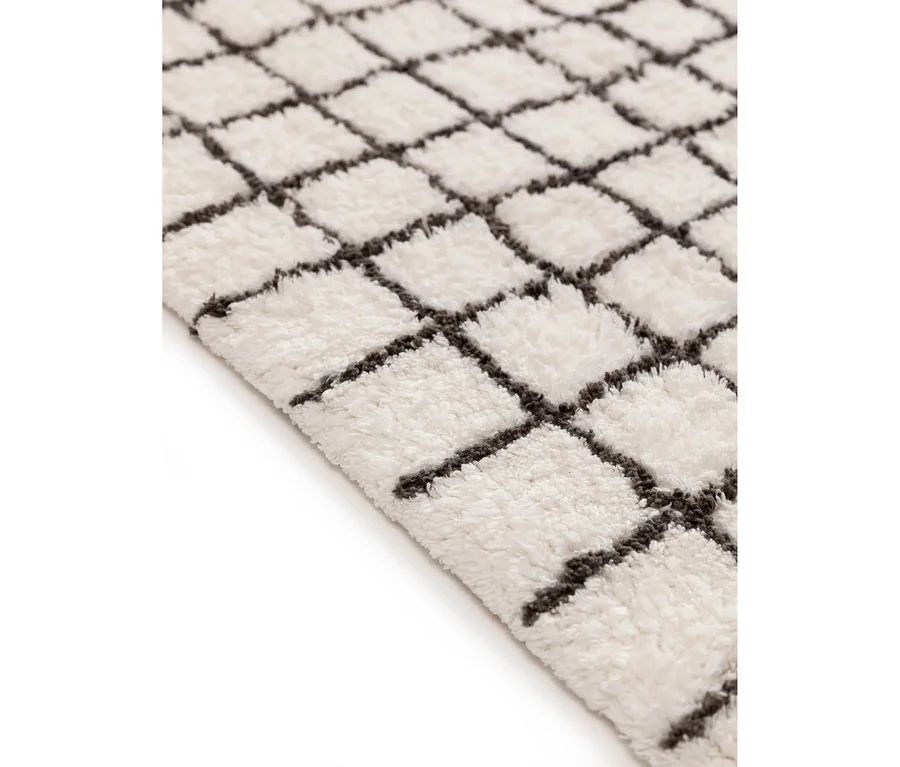 Nahaufnahme einer benuta Badematte »Wavu« (60 x 100 cm) mit flauschiger, weißer Oberfläche und einem grauen Gittermuster.