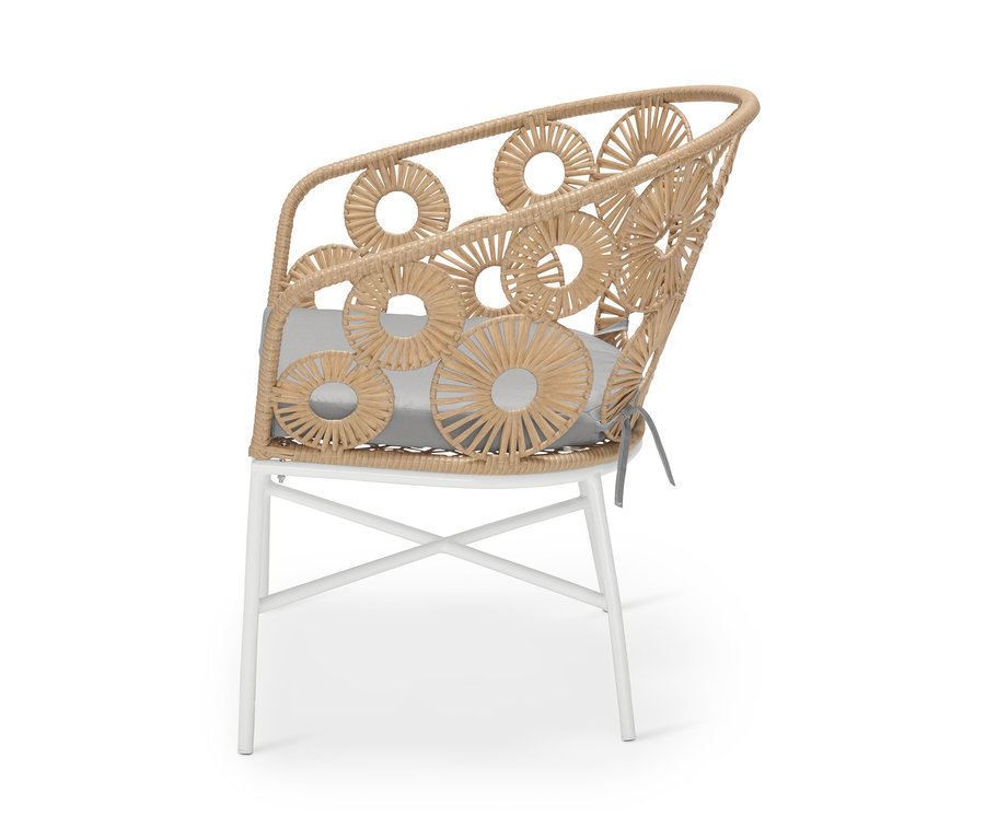Detailansicht eines Sessels mit Blumenmuster, mit beige-farbenem Rattangeflecht und weißen Metallbeinen.
