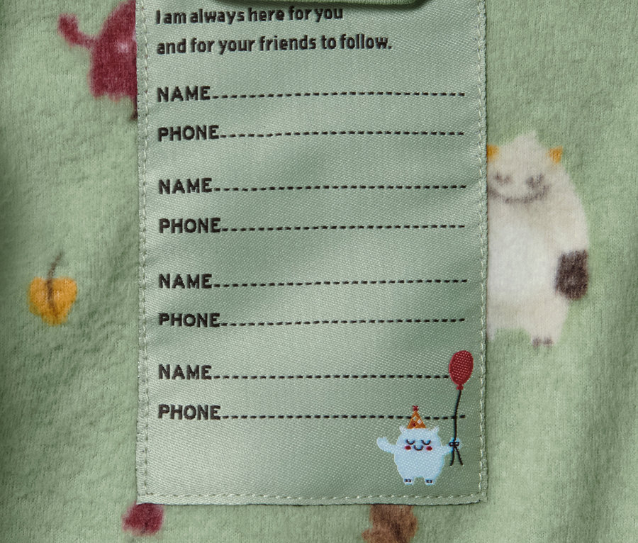 Detailansicht einer Fleecejacke mit Monsterprint und einem Etikett für Name und Telefonnummer.