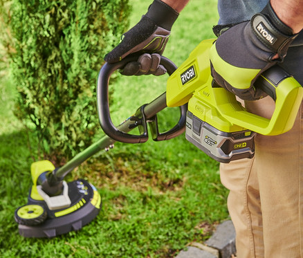 Mann trimmt Rasen mit RYOBI 18 V One+ Akku-Rasentrimmer mit Radführung.