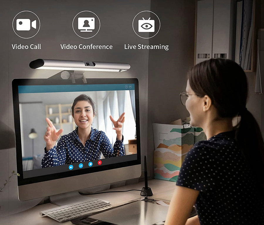 Eine Frau sitzt an einem Tisch und führt einen Videoanruf auf einem Monitor, über dem eine 2-in-1-LightBar-Pro-Monitorlampe mit Full-HD-Webcam angebracht ist.
