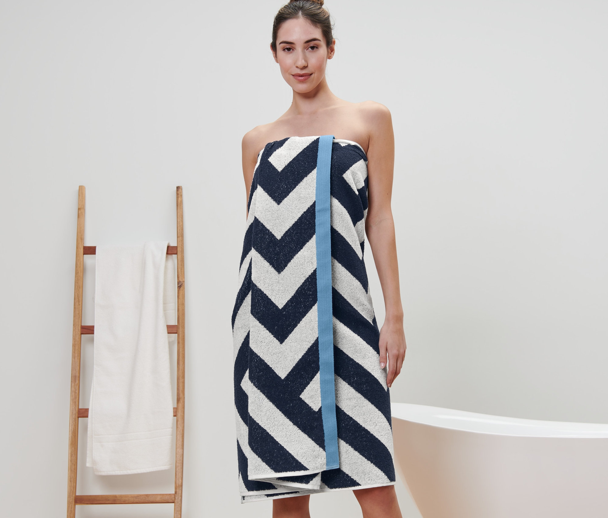 Eine Frau, eingewickelt in ein XL-Badetuch mit Grafikmuster.