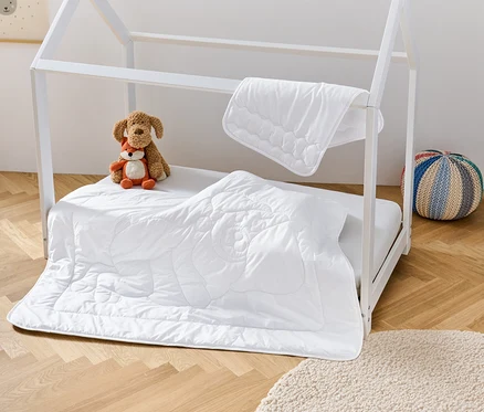 Weißes Kinderbett mit irisette® greenline Kinder-Steppdecke und -Kissen, Stofftieren und Hocker.