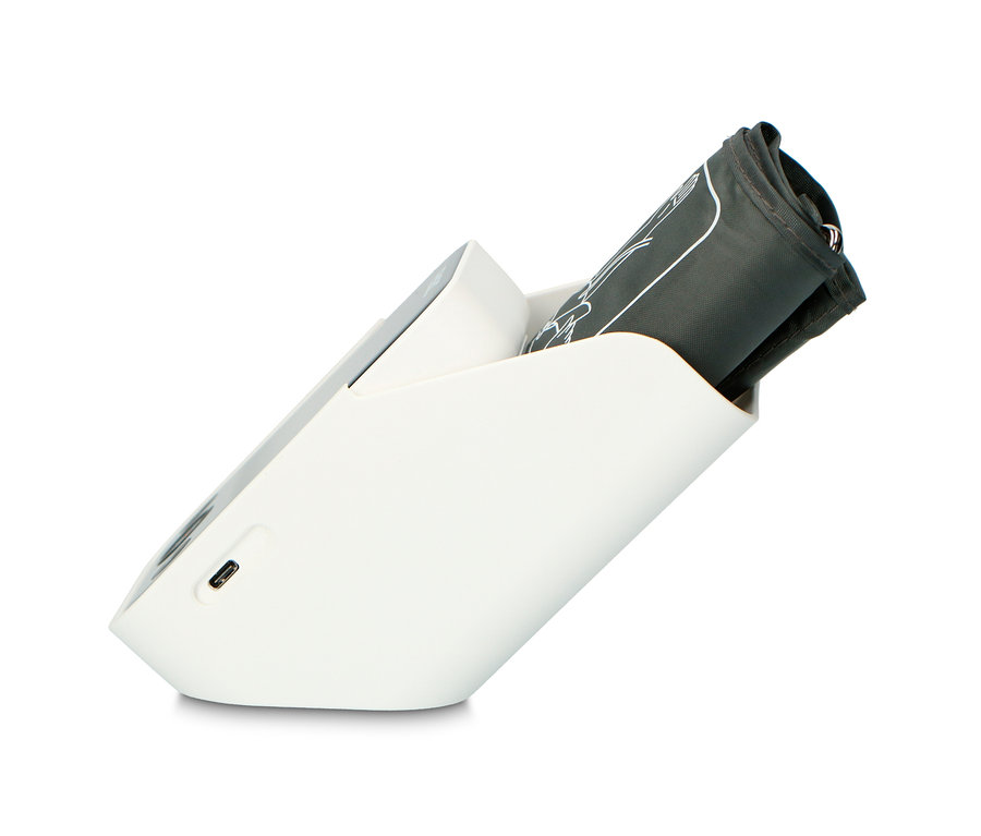 Eine zusammengerollte Manschette eines schwarzen Oberarm-Blutdruckmessgeräts wird in einer weißen Basis aufbewahrt.