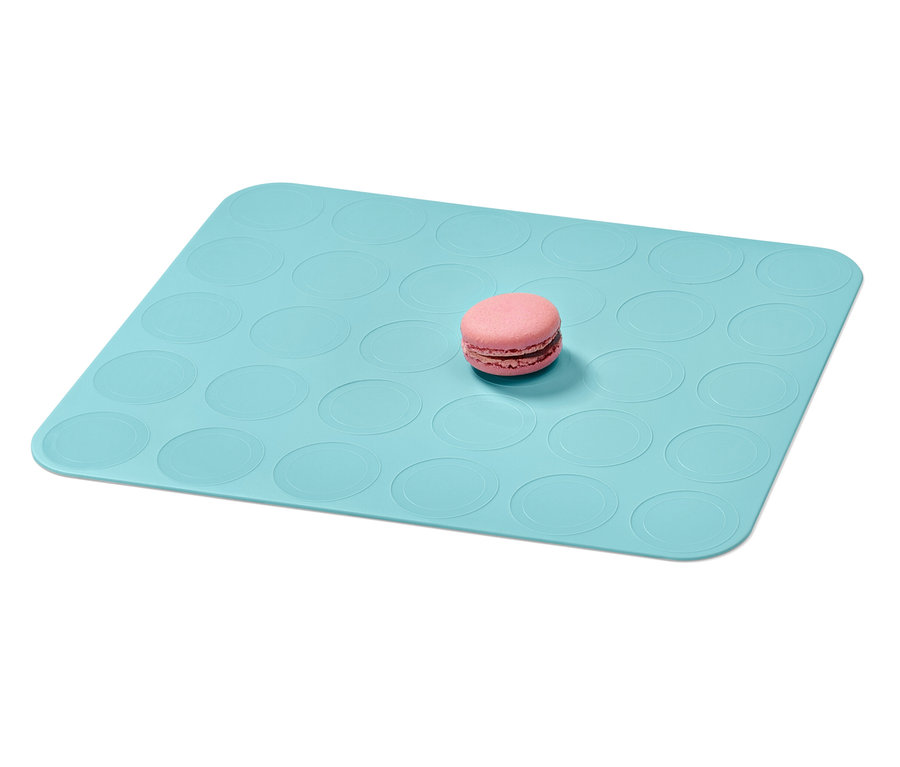 Ein rosa Macaron liegt auf einer blauen Macaron-Backmatte.
