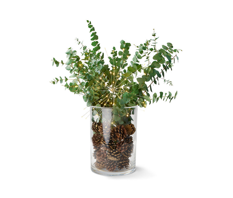 Dekoration in einer Glasvase: Tannenzapfen, Eukalyptus und ein LED-Leuchtzweig.