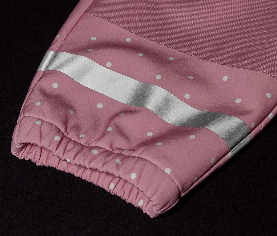 Detailansicht eines Kinder-Softshell-Einteilers mit rosa Ärmel, weißen Punkten und Reflexstreifen.