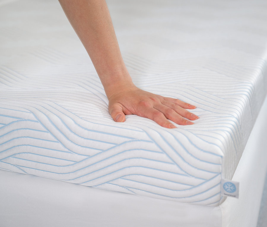 Eine Hand berührt den TEMPUR Pro® Plus SmartCool™ Topper mit blauen Wellen.