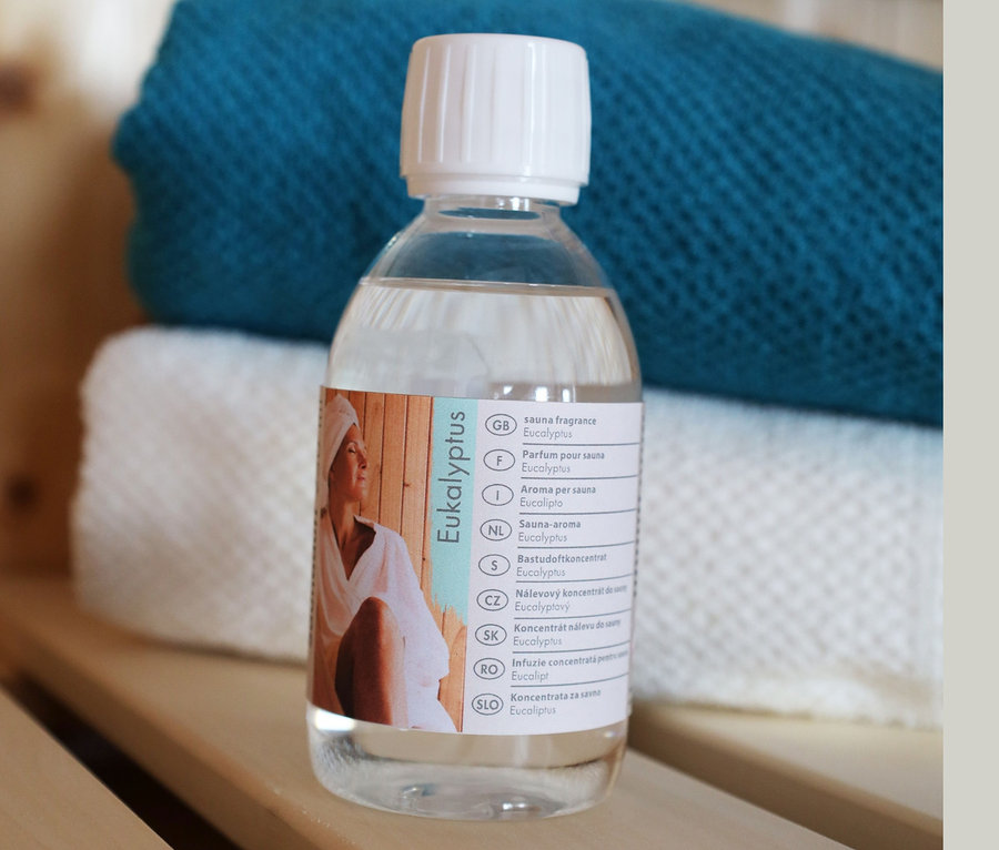 Eine Flasche Eukalyptus steht auf einem Holzregal vor Handtüchern.
