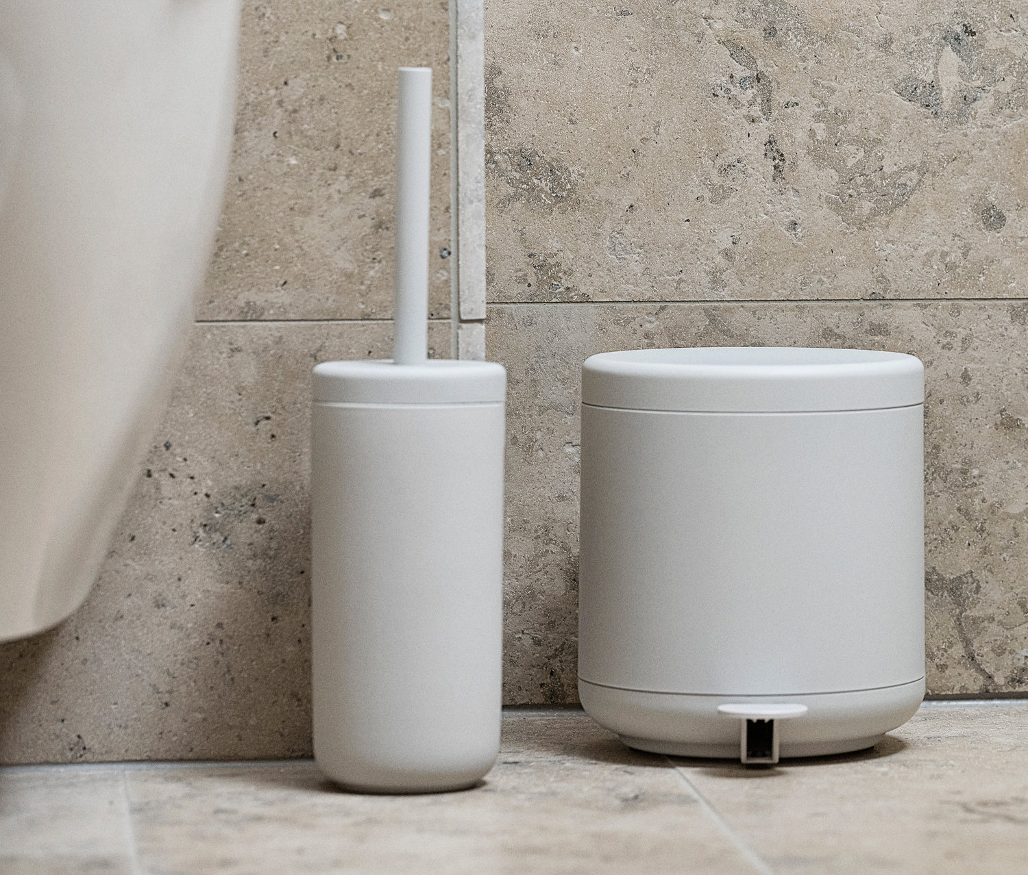 Eine weiße und eine hellgraue ZONE DENMARK WC-Bürste »Ume« stehen nebeneinander im Badezimmer.