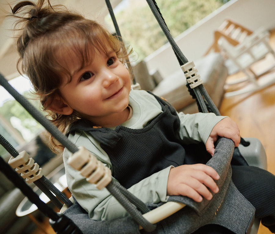 Kind sitzt in grauer HUDORA Schaukelaufsatz Toddler.