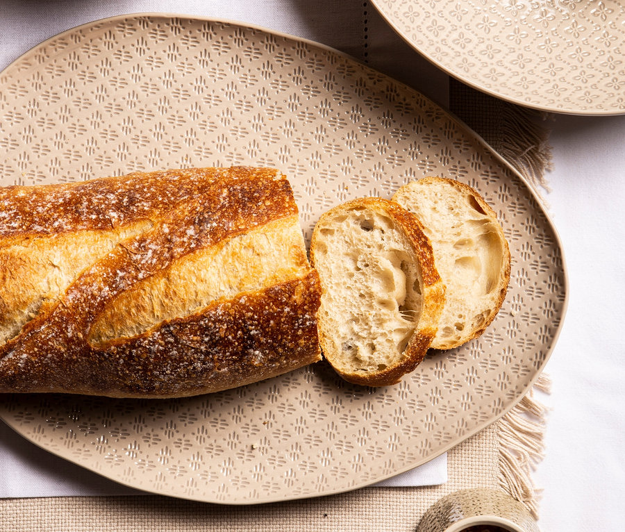 Brot und Brotscheiben liegen auf einem ovalen Servierteller "Tirari".