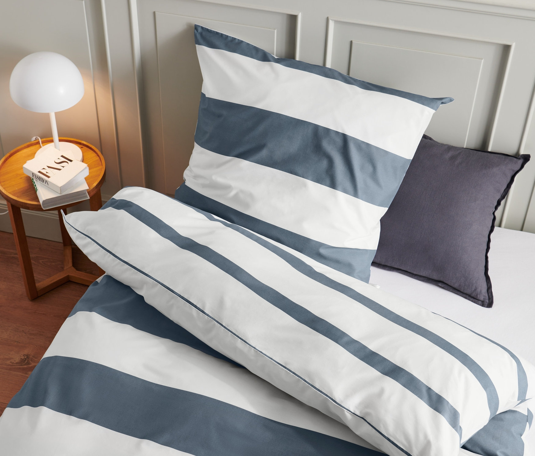 Nahaufnahme von blau-weiss gestreifter Bettwäsche: drei Premium-Baumwoll-Bettwäsche-Sets in Normalgröße und ein Premium-Baumwoll-Bettwäsche-Set in Übergröße.