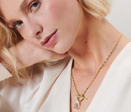 Blonde Frau mit Kette mit Glasanhänger.