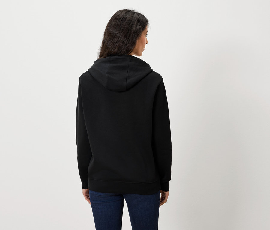 Rückansicht einer Frau in schwarzem Kapuzenpullover und blauen Jeans.