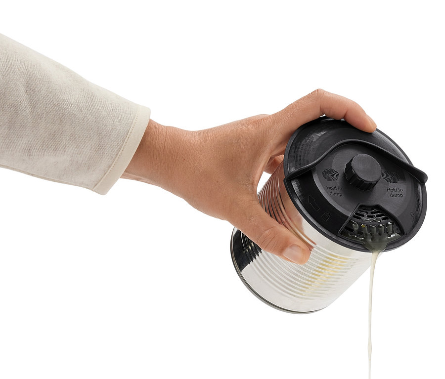 Eine Hand neigt eine Dose mit schwarzem Deckel und gießt Flüssigkeit aus.