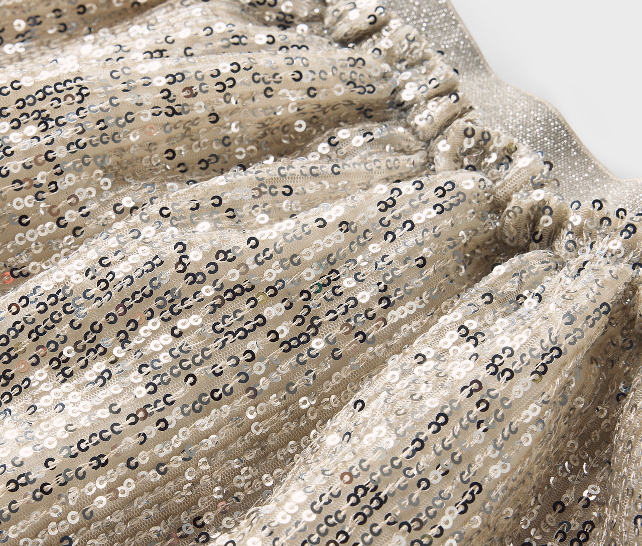 Detailaufnahme eines silbernen Paillettenrocks mit elastischem Bund.