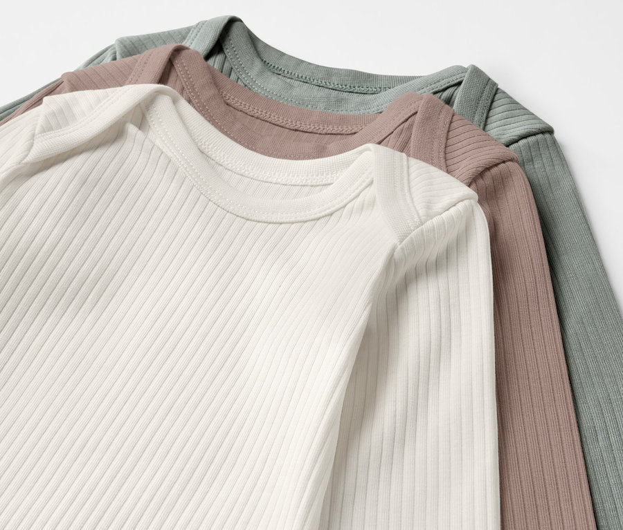 Drei Baby-Ripp-Langarmbodys in Weiß, Braun und Grün.
