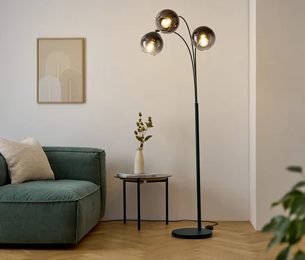 Wohnzimmer mit Sofa, Tisch und Stehlampe.
