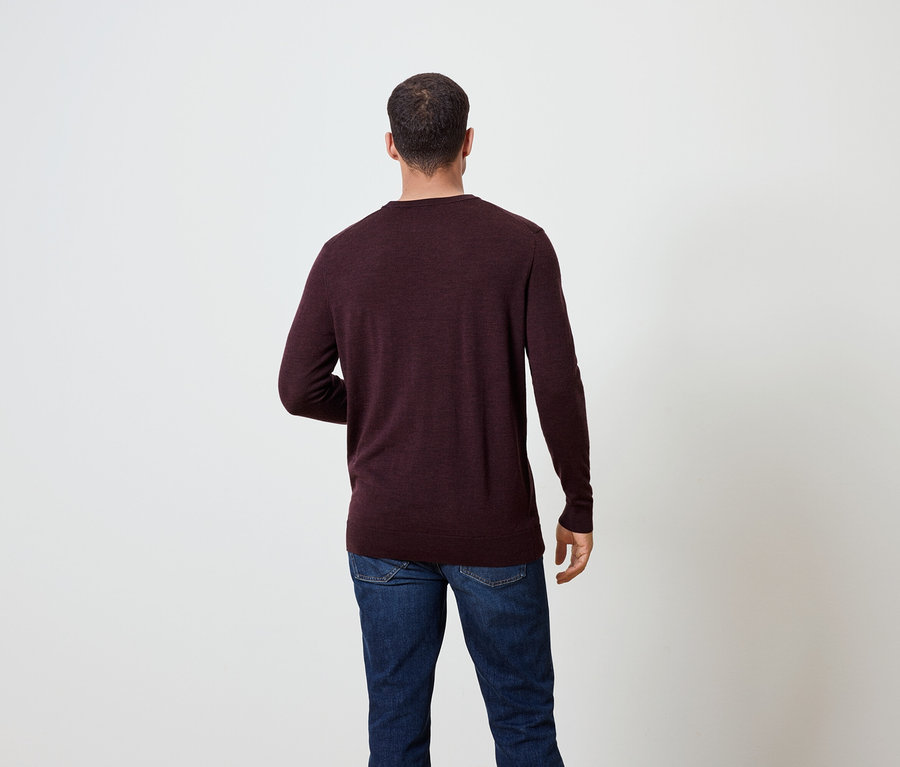 Mann von hinten trägt einen burgunderroten Pullover und Jeans.