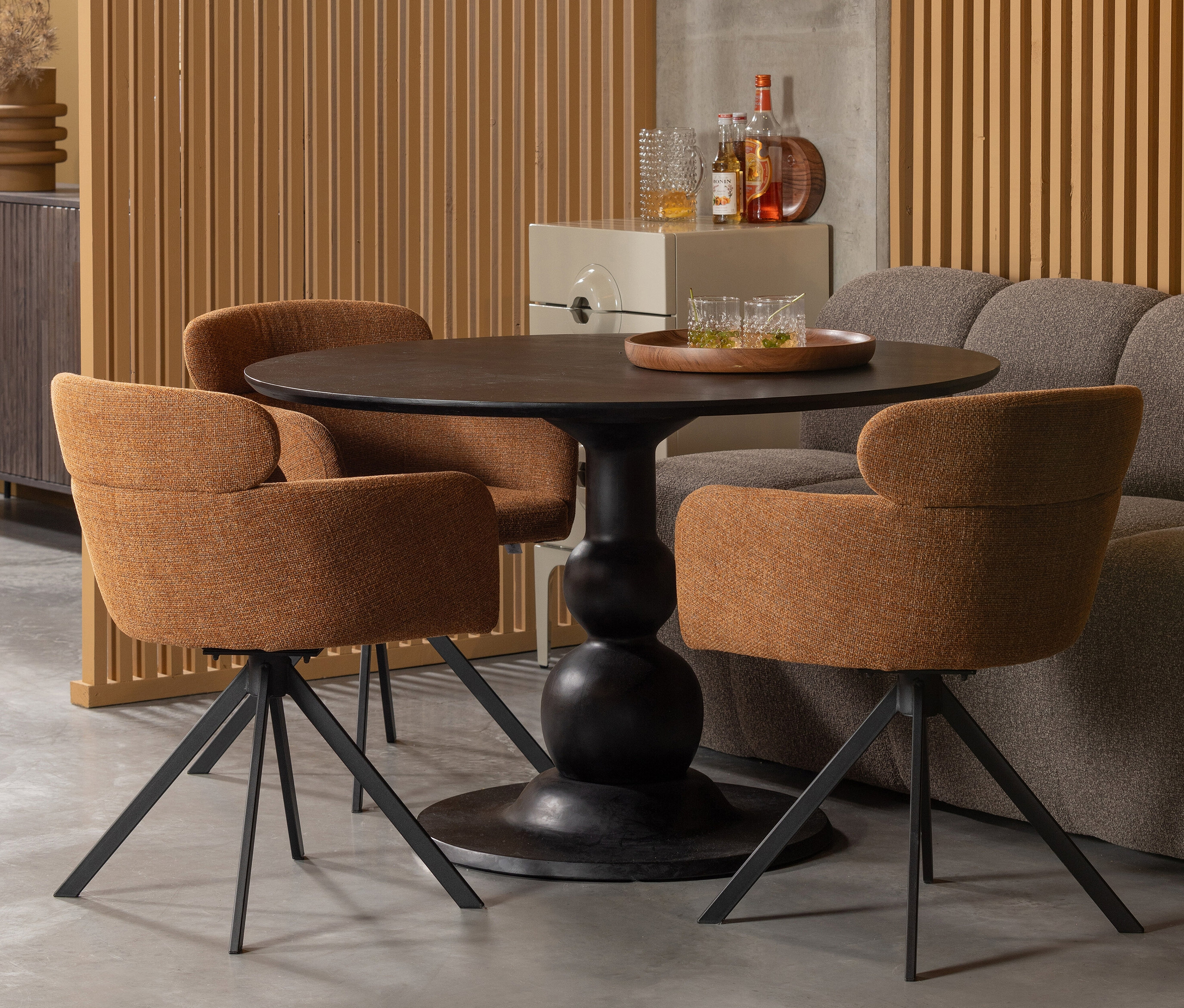 Drei Woood »Fenne« Stühle im 2er-Set in Ginger Farbe stehen um einen runden Tisch.