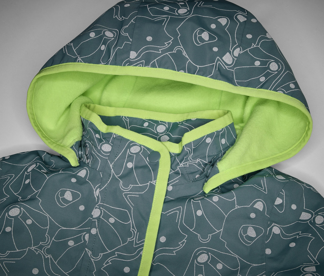 Detailansicht einer Kinder-Thermo-Regenjacke mit reflektierenden Elementen, Kapuze und Tiermuster.