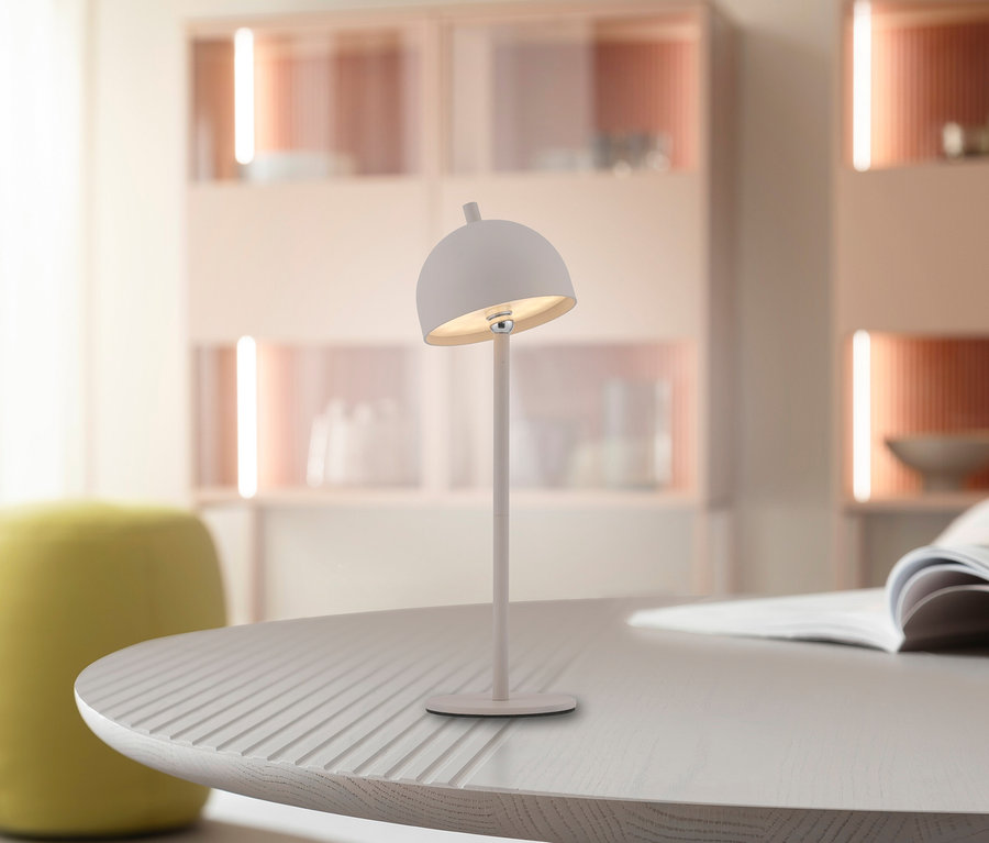 Weiße Lampe steht auf rundem Tisch, im Hintergrund Schränke.