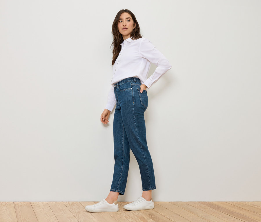 Frau posiert in blauen Mom Jeans – Fit »Nyla« und weißem Hemd.