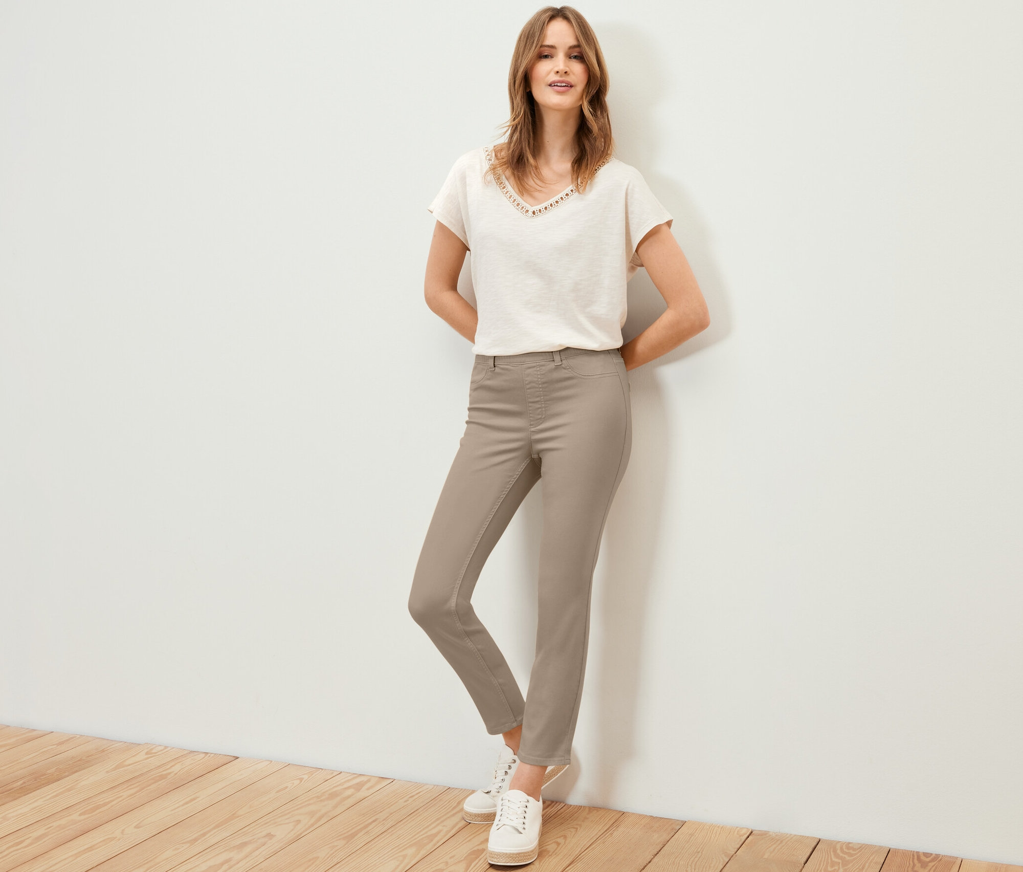 Frau posiert in 7/8-Treggings, T-Shirt und Turnschuhen.