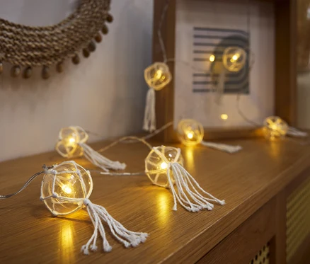 LED-Kugel-Lichterkette liegt auf einer Holzkommode.