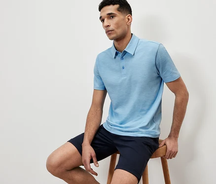 Mann sitzt auf einem Hocker und trägt ein blaues Poloshirt.