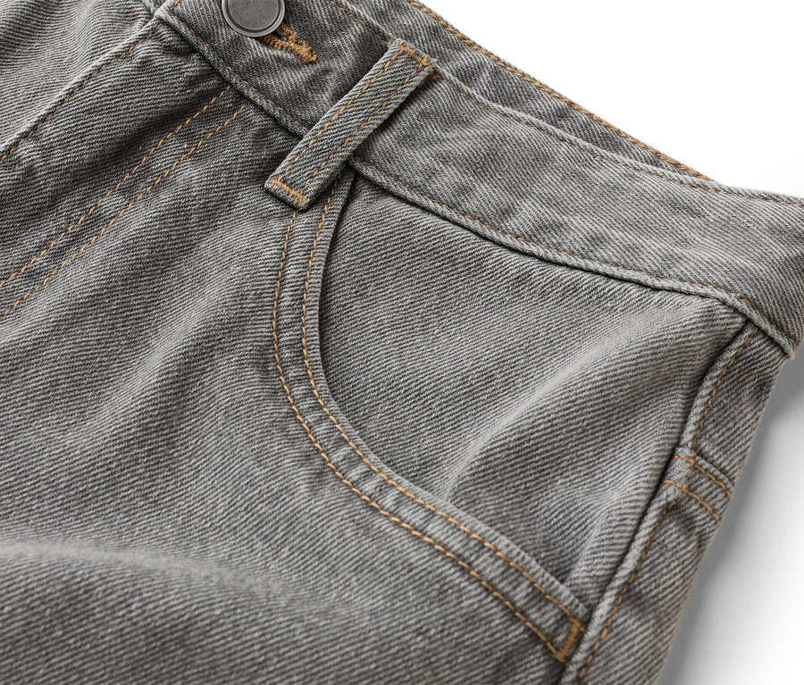 Detailaufnahme einer grauen Jeans mit Hosentasche und Knopf.