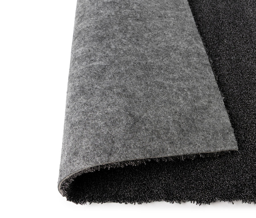 Nahaufnahme eines anthrazitfarbenen Teppichs »Jane« mit aufgerollter Ecke, die die graue Unterseite zeigt.