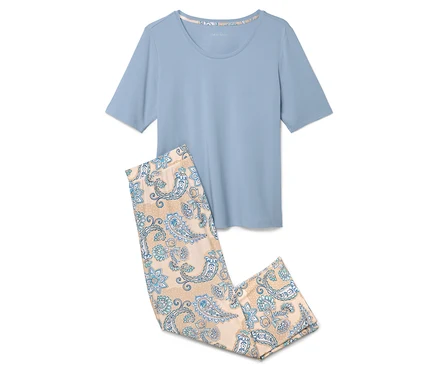 Ein hellblaues Pyjama-Oberteil liegt neben einer hellbraunen Pyjamahose mit blauem Blumenmuster.