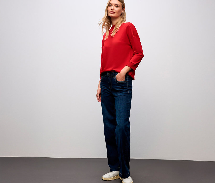 Frau mit rotem Street One T-Shirt mit Rippdetail und Jeans.