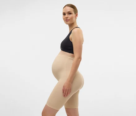 Schwangere in Sport-BH und hautfarbenen MAMALICIOUS Skinny Shorts »MLTIA JEANNE«, schwarz, seitlich vor weißem Hintergrund.