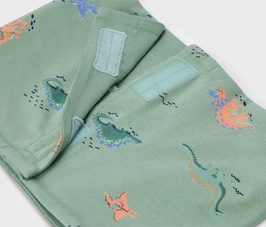 Nahaufnahme einer hellgrünen Hose mit Dinosaurier-Muster und Klettverschluss.